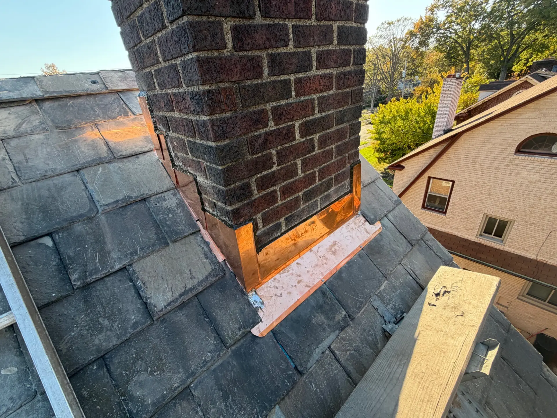 Copper flashing fitted around a brick chimney on a slate roof